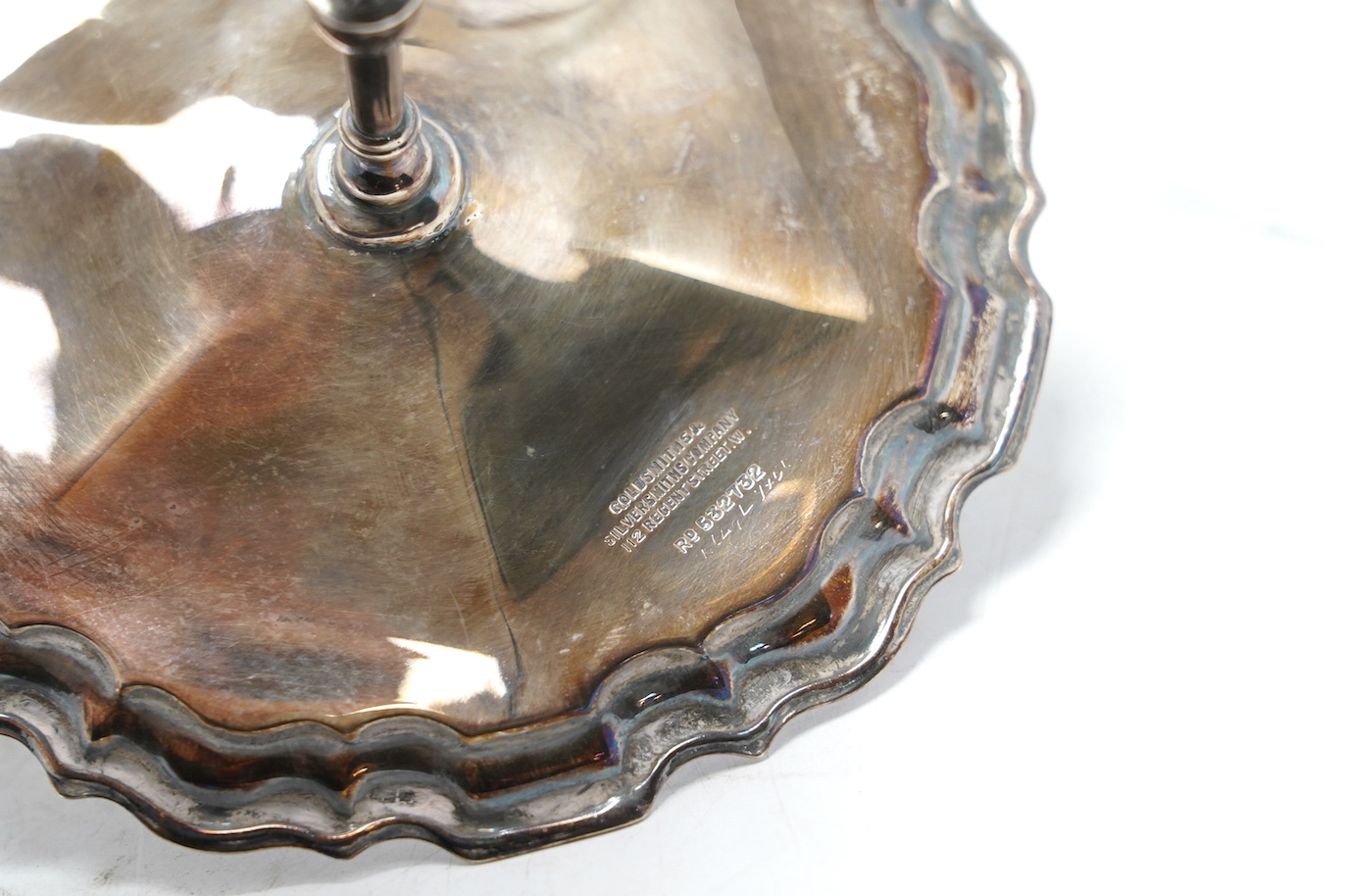 An Edwardian silver miniature model of a tripod table with piecrust border, Goldsmiths & Silversmiths Co Ltd, Sheffield, 1908, diameter 11.1cm, together with a French 950 standard white metal sugar caster, 7.3oz. Conditi
